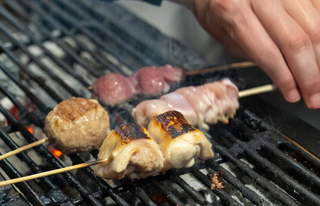 炭火の網の上で焼き上がっていく焼鳥の串
